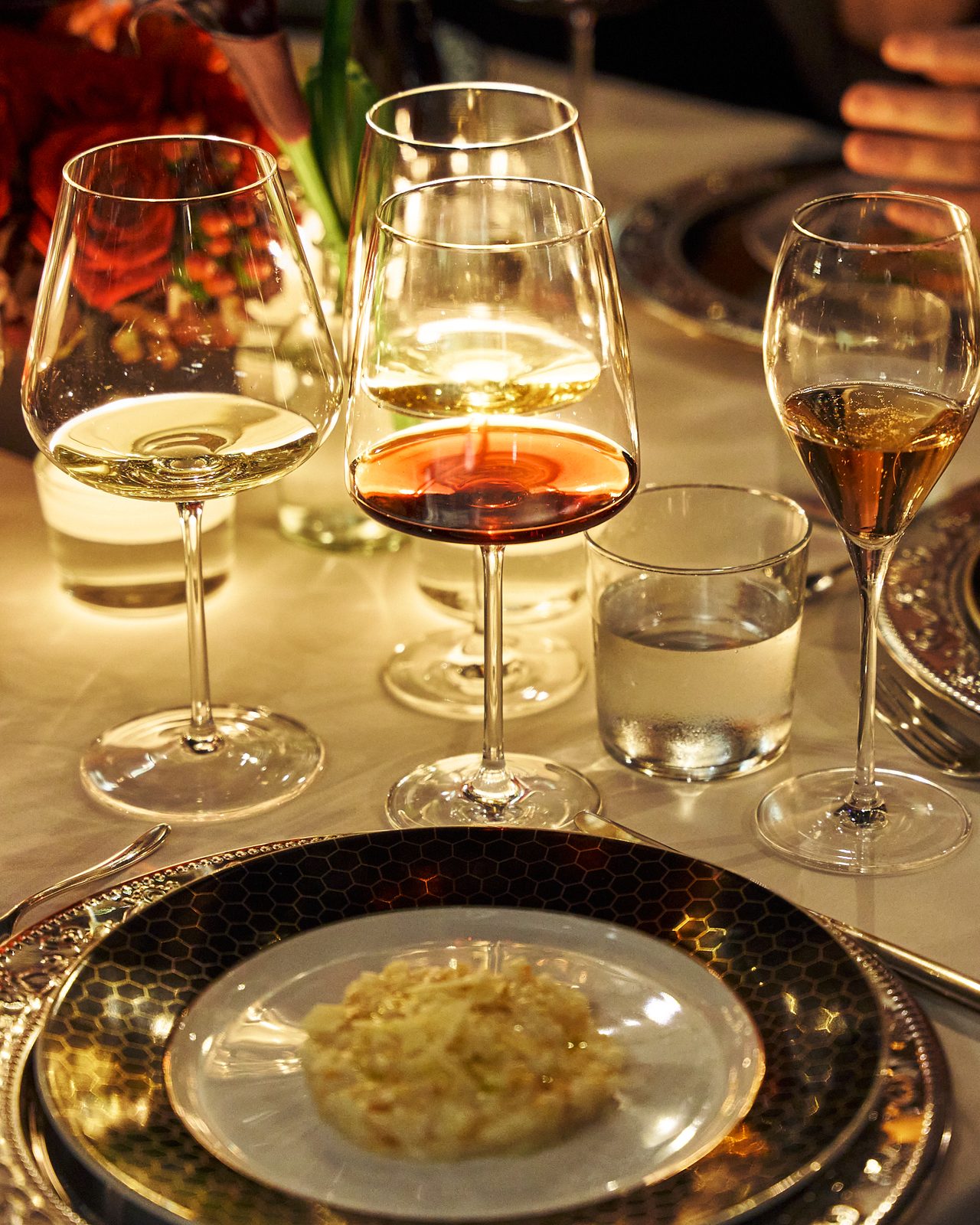 Glasses of red and white wine above a plate on a hexagon-patterned charger
