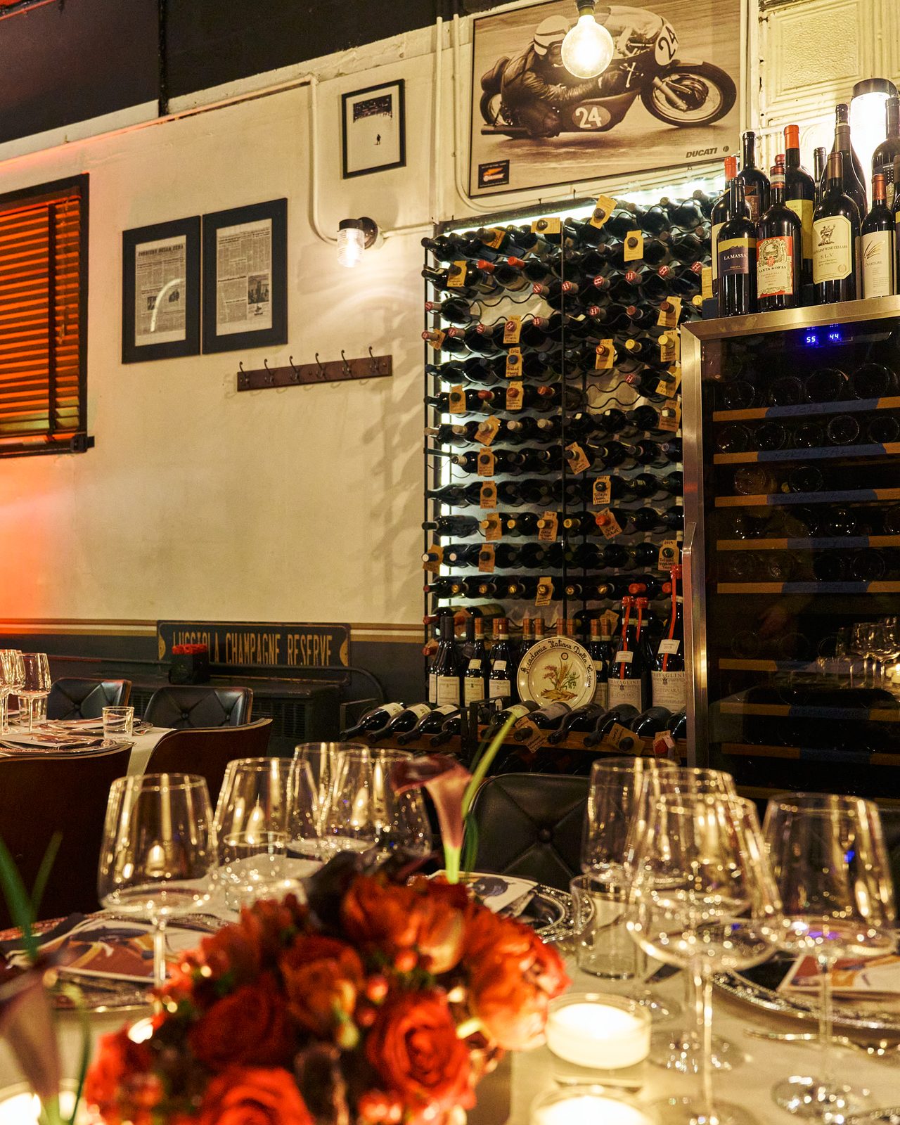 The table set for dinner in the wine cellar, glasses and red flowers, bottles on the wall