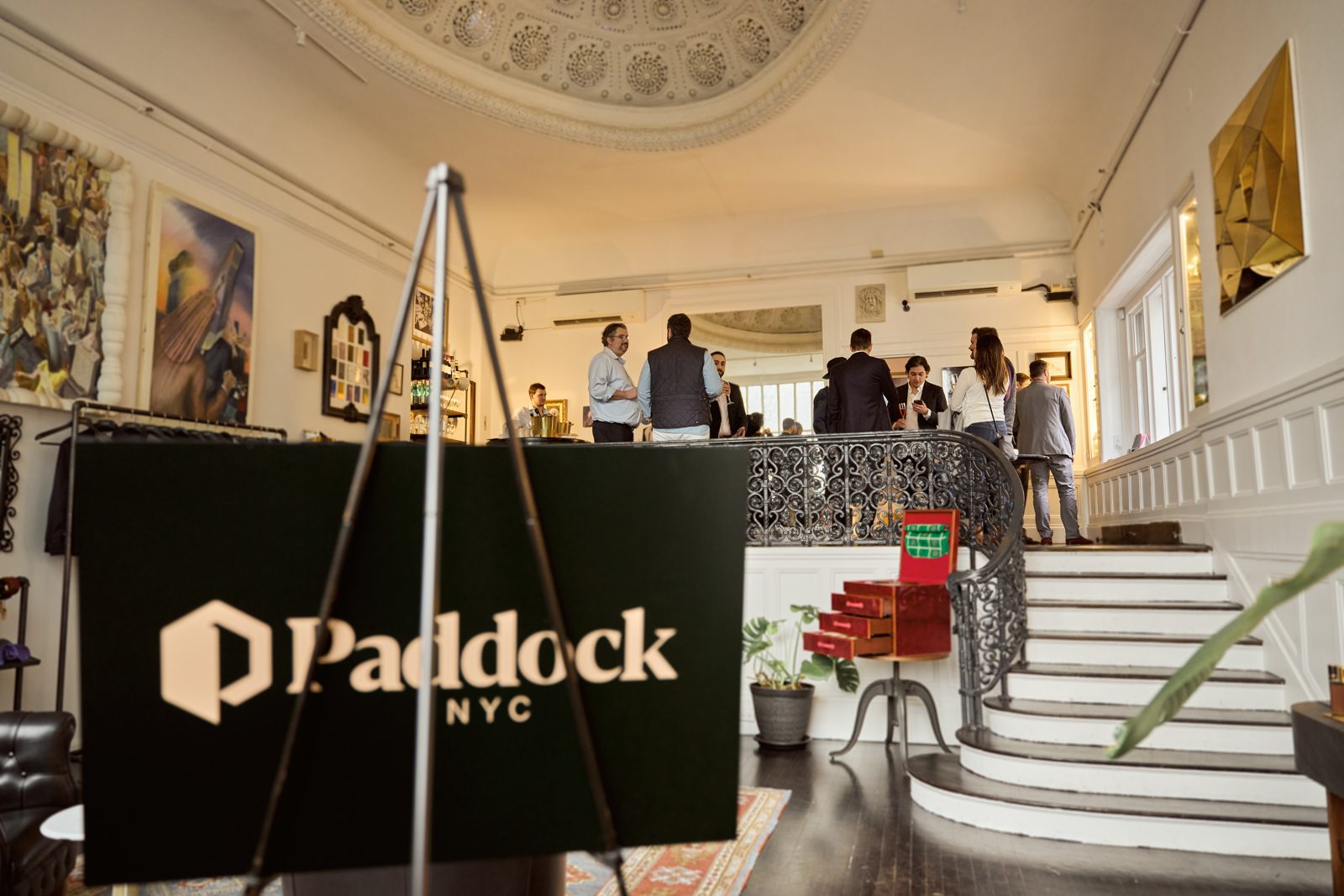 The Paddock NYC sign on an easel in a crowded atelier room